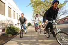 3 kids on bikes on the sidewalk