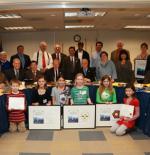 award ceremony. people are standing in two rows, the people in the first row are children holding awards