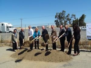 nine people in suits digging a hole at a groundbreaking event