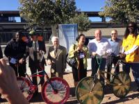 5 people in professional clothing standing behind 2 bikes