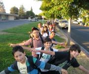 kids lined up on the sidewalk with school backpacks